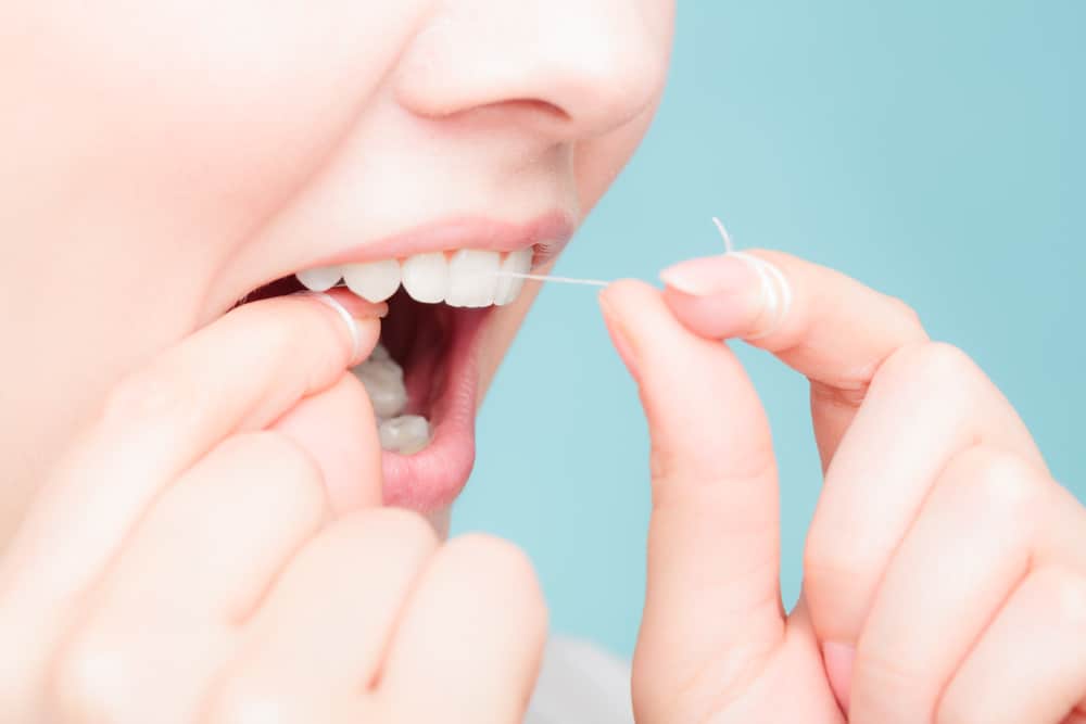 Woman with healthy smile and white teeth flossing