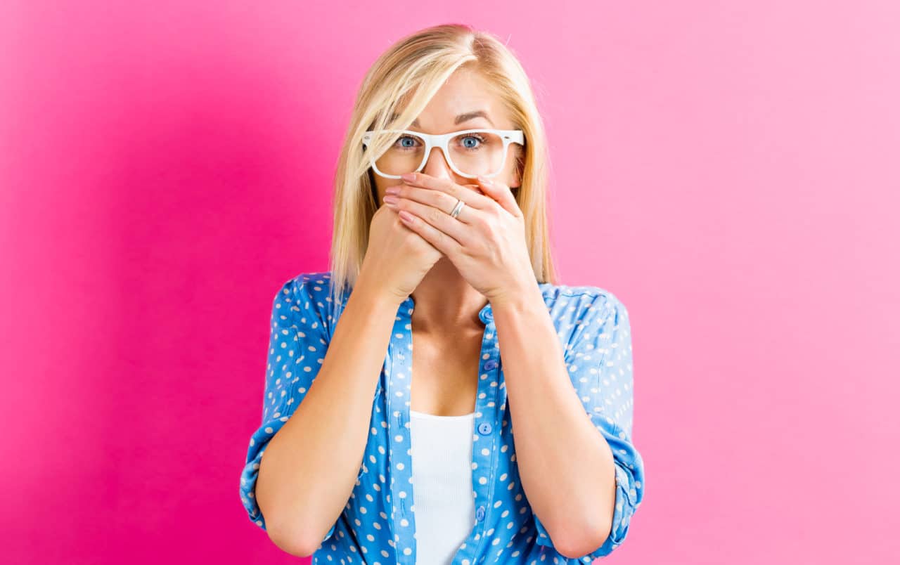 Young woman covering her mouth on a pink background