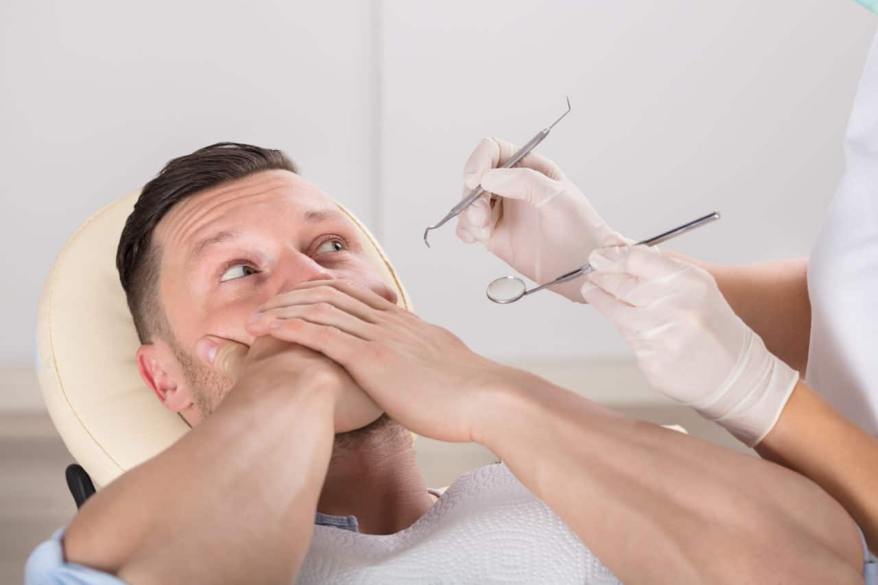 Man Covering His Mouth With Hands While Having Dental Checkup In Clinic Sedation Dentistry