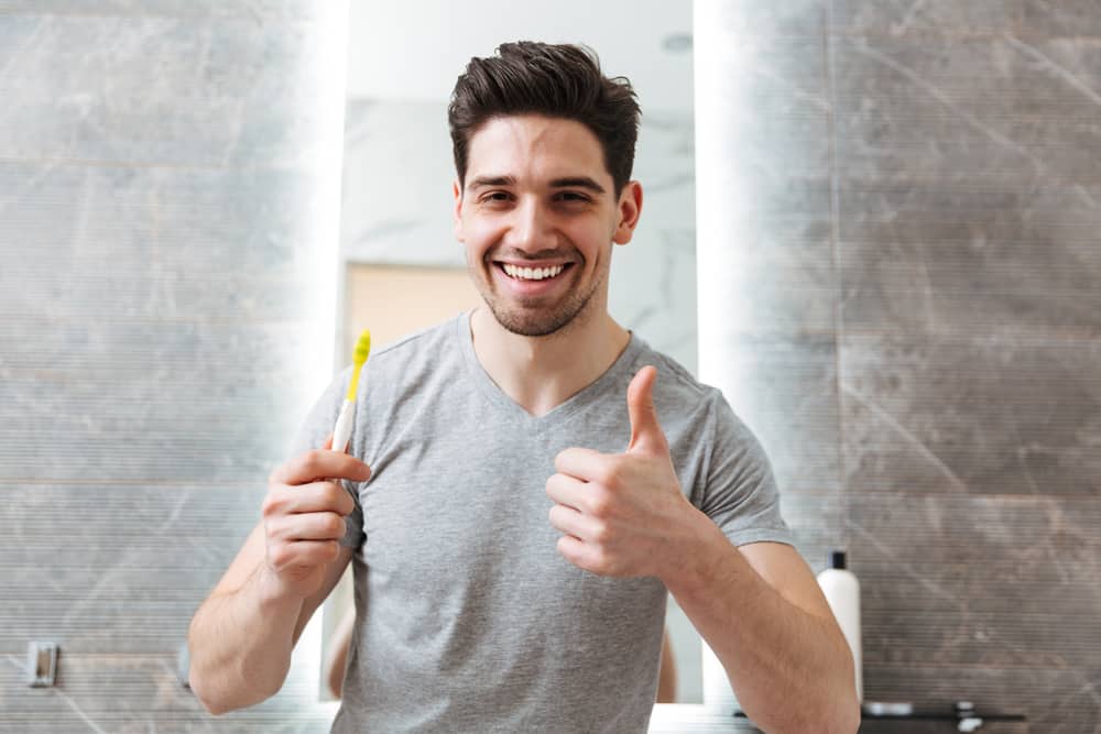 Young brunette man brushing teeth with healthy smile and no mistakes.