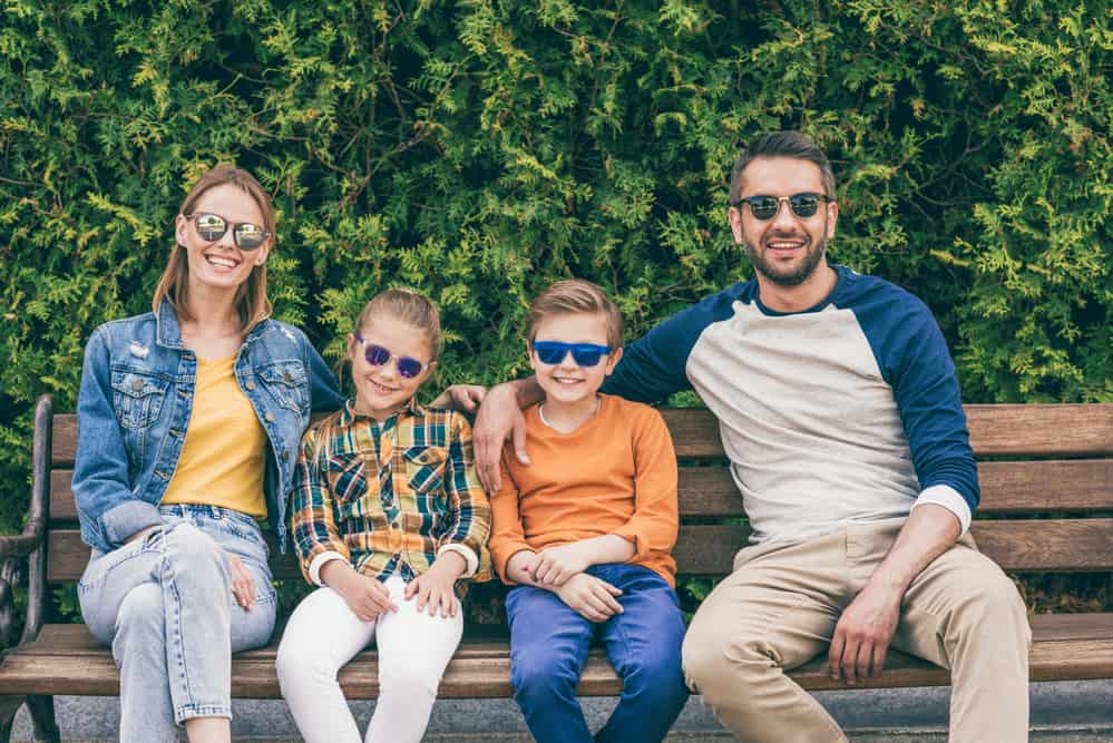Young Family Smiling Wearing Sunglasses in a park
