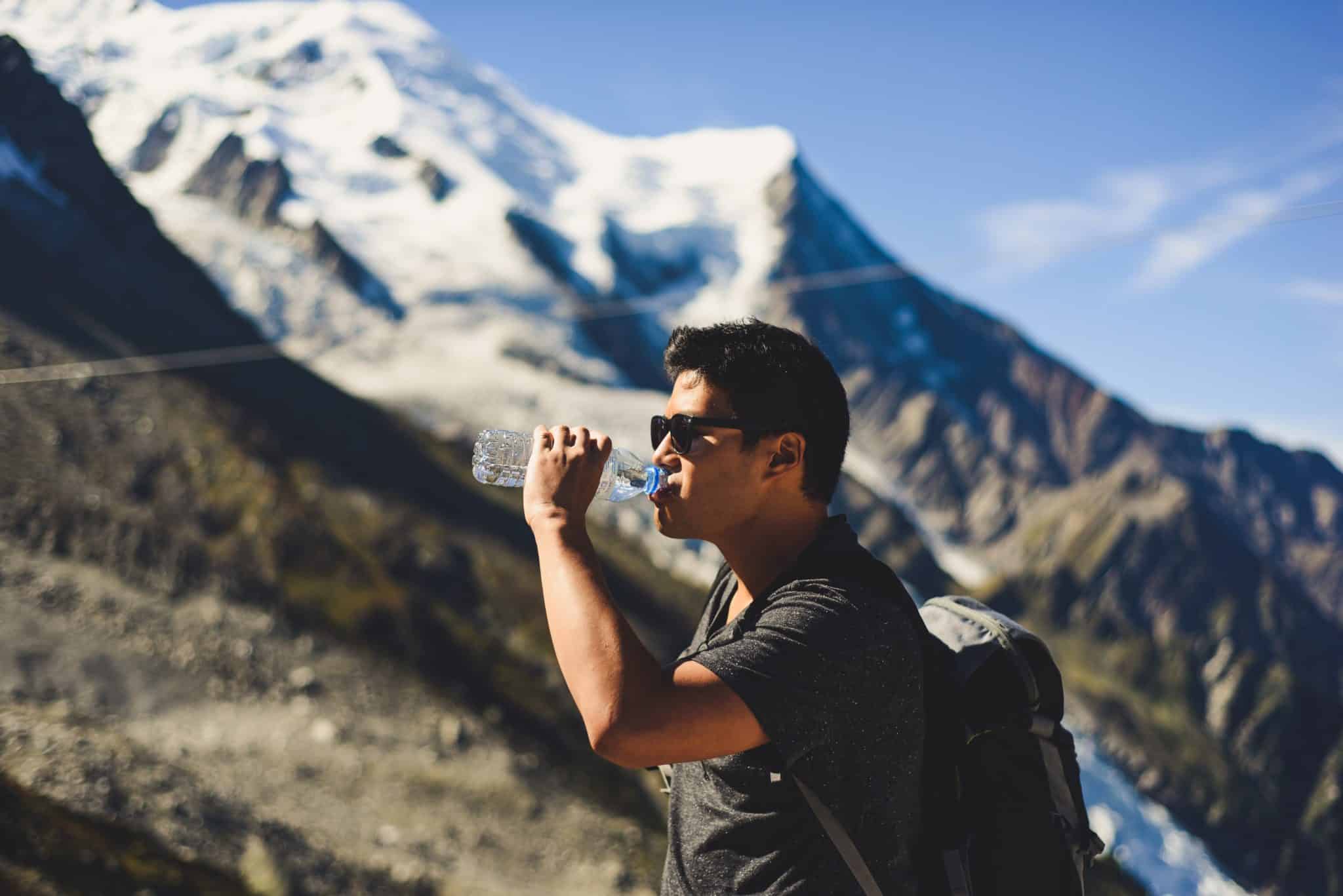 man drinking water on snowy mountain