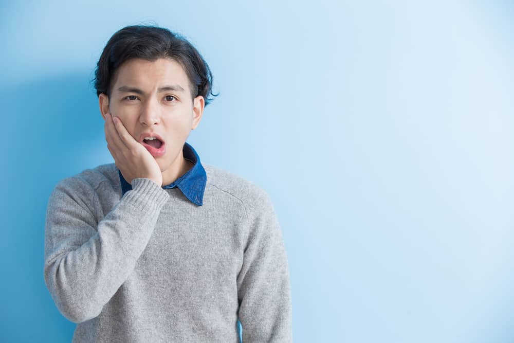 man feel toothache with blue background, asian wisdom tooth