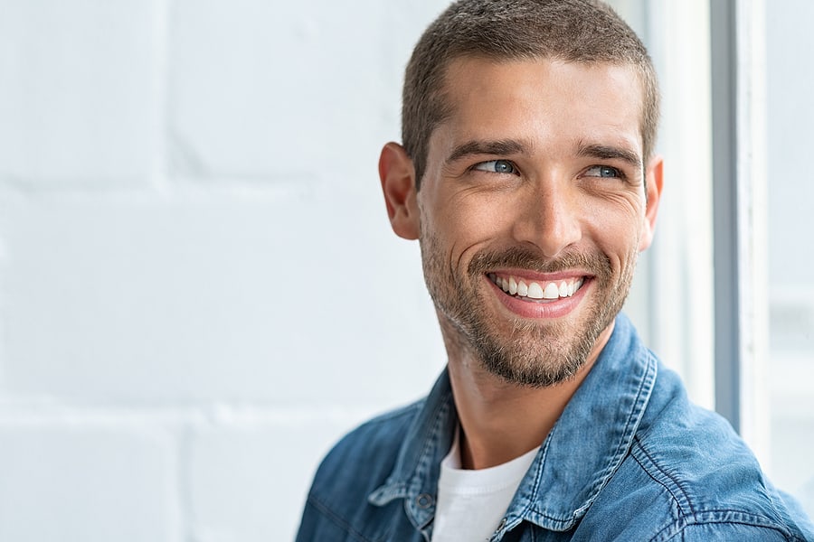 man with dental implants wearing blue shirt