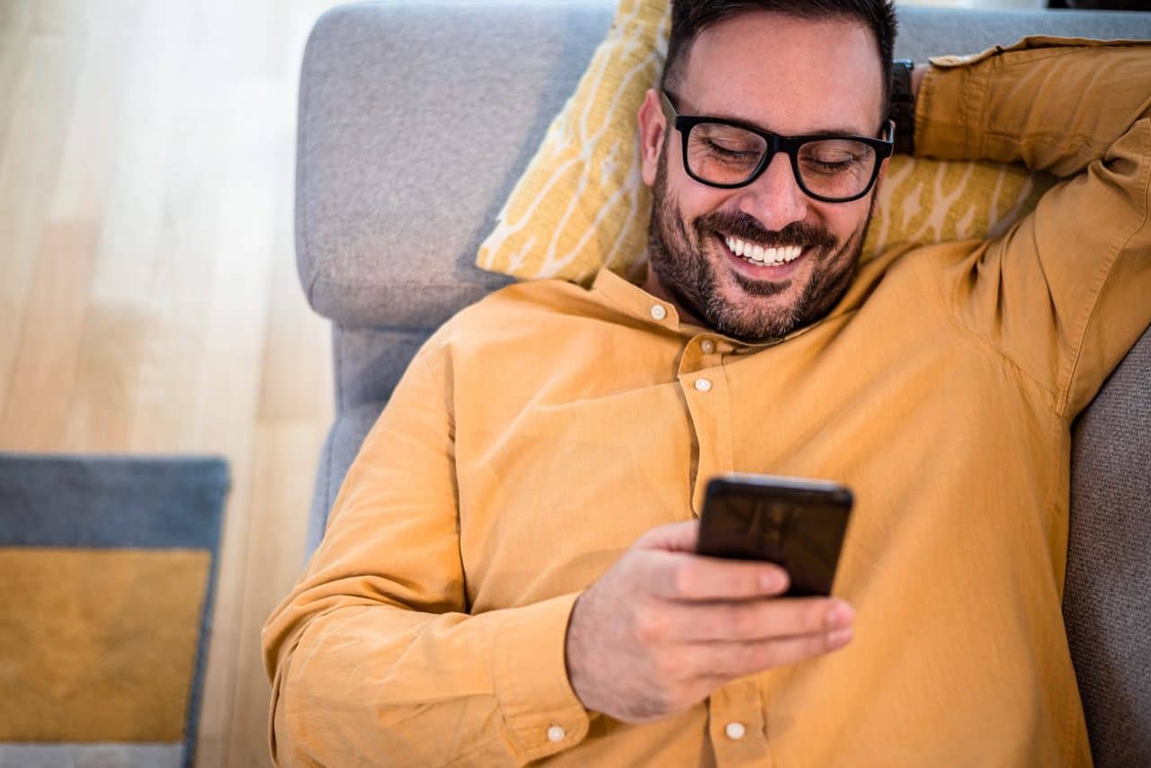 Man looking at cell phone sitting on couch