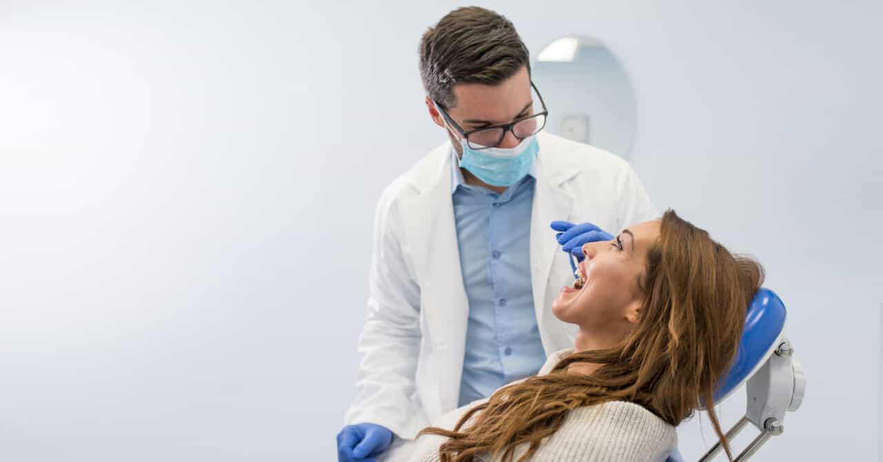 Male dentist examining woman patient for oral health reasons.
