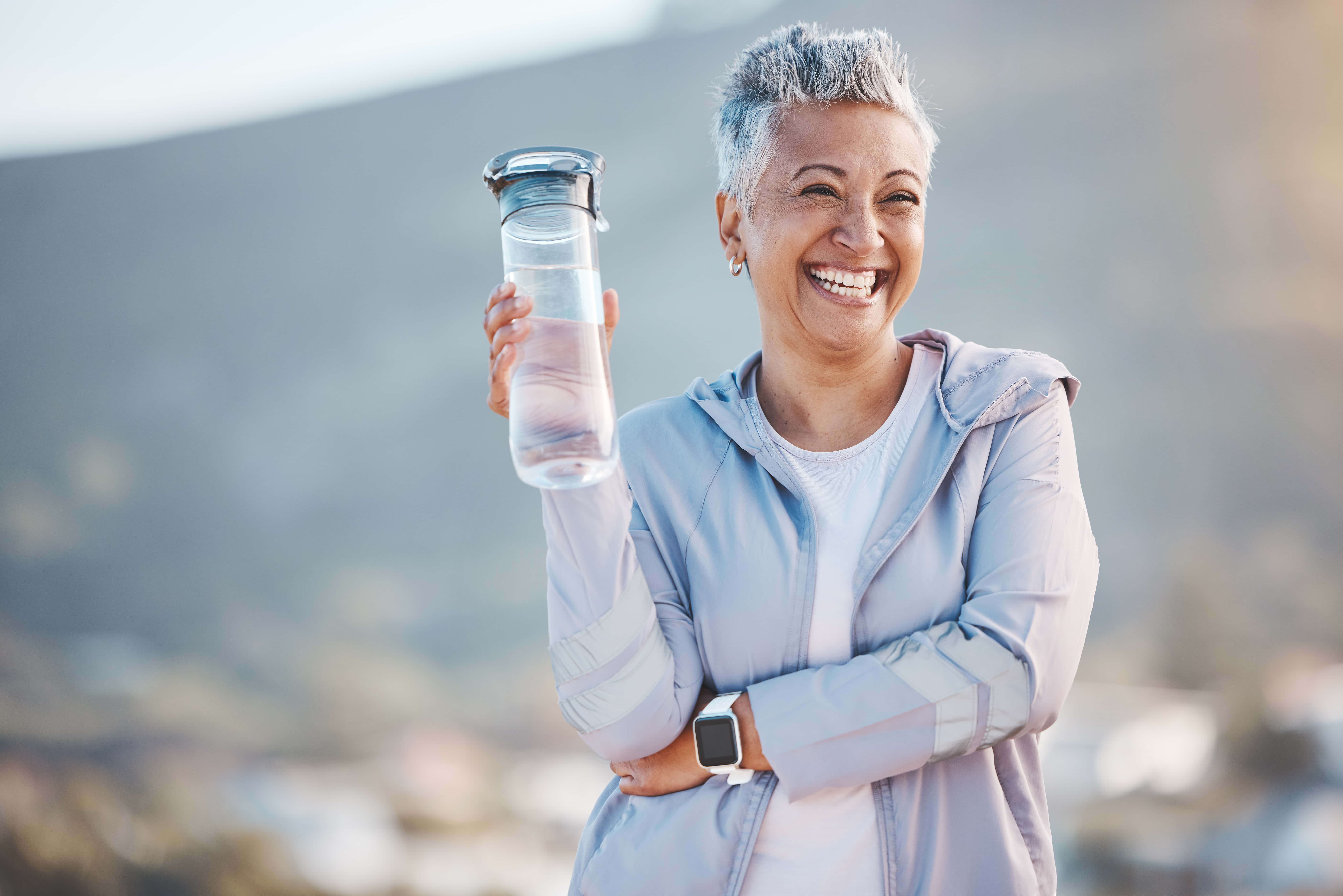 Happy mature woman with healthy smile holding water bottle.