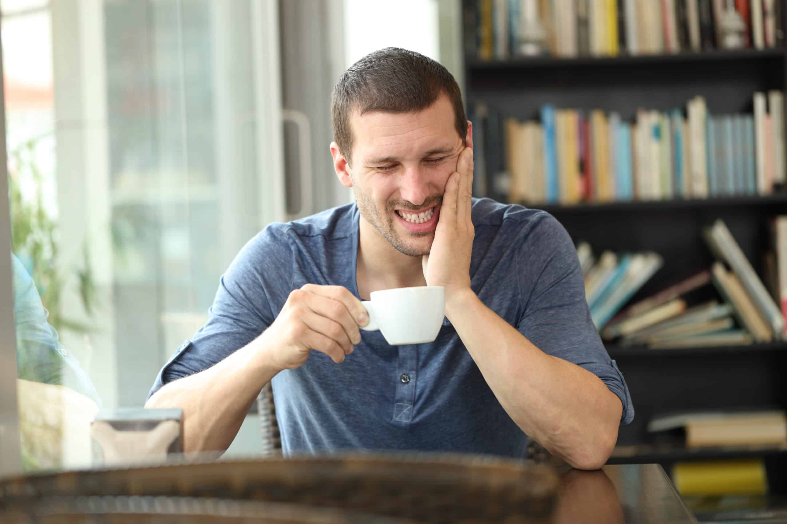 Man drinking coffee reacts to hot beverage with sensitive teeth.