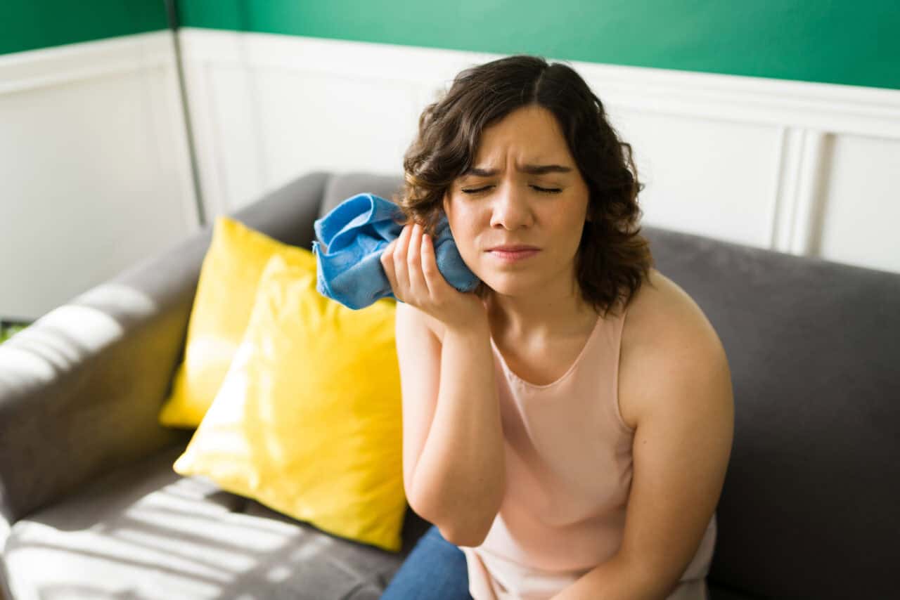 Woman holding a cold compress on her toothache. 
