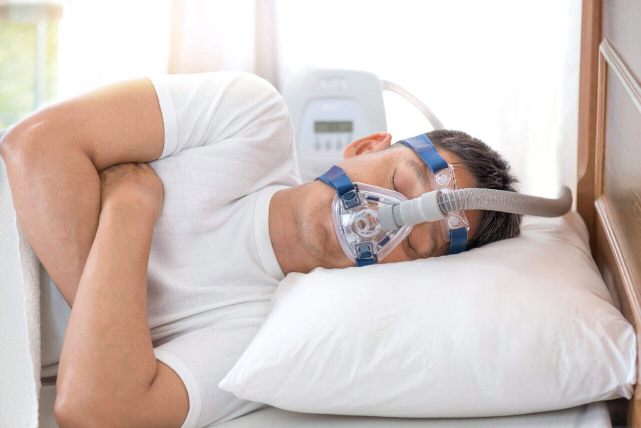 A man with Sleep Apnea using his CPAP machine. 